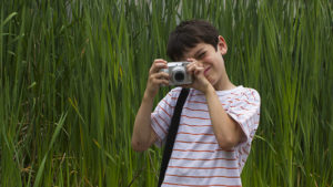 Young boy taking a photo with grassy background